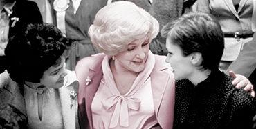 Mary Kay Ash fica seus braços em volta de duas mulheres e às ouve enquanto falam.